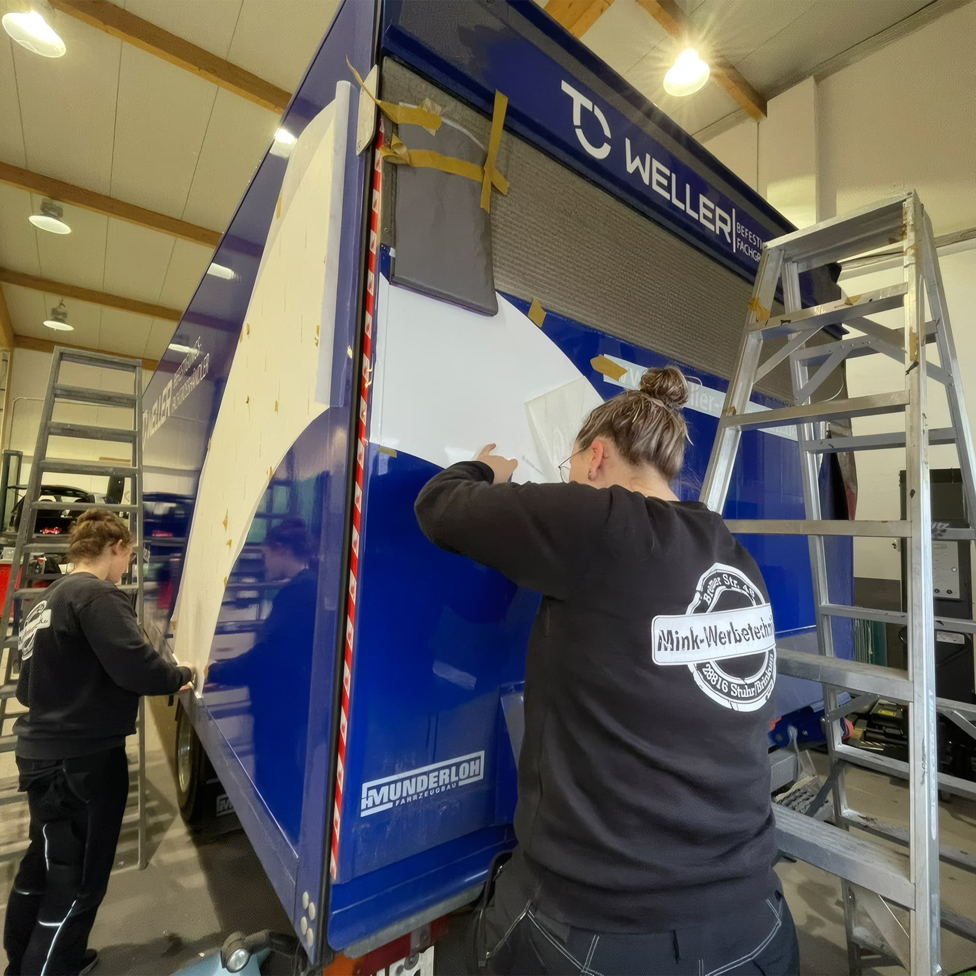 Mitarbeiter beim Folieren eines LKW-Anhängers